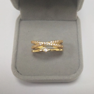 Detail of gold layered crossover ring with micro-paved cubic zirconia in a velvet box