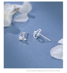 Macro detail of silver moon and star earrings with sparkling cubic zirconia inlay
