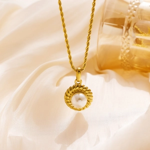 Detailed view of a gold pearl pendant necklace with twisted border on silk fabric