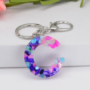 Detail of letter C keychain made of colorful stone resin with silver metal ring and hook