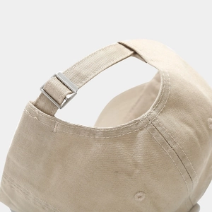 Detail of adjustable metal buckle and stitching on beige cotton baseball cap back