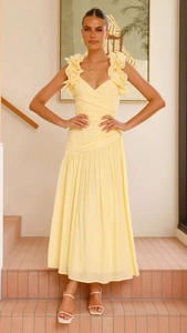 Détail d'une robe longue jaune à col en V avec épaule volantée et texture plissée à la taille