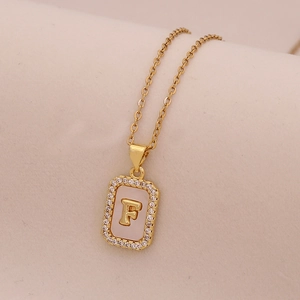 Gros plan du pendentif rectangulaire en or 18 carats avec nacre blanche, cristaux et lettre F