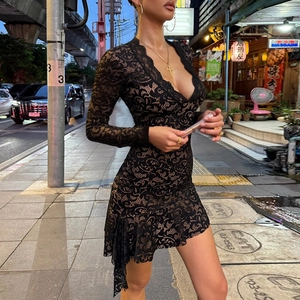 Elegant black lace mini dress with long sleeves and V-neck on a city street background