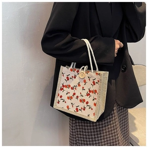 Detail of floral tote bag featuring red flower print, rope handles and wooden button