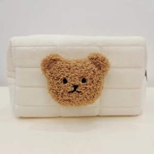 Close-up of white quilted fabric bag with brown plush bear embroidery for stationery