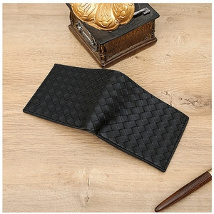 Detail of black woven leather men's wallet showing premium texture on wood background
