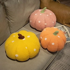Plush pumpkin throw pillows with white polka dots on a sofa in yellow, orange and pink