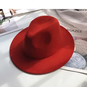 Detailed view of a stylish red wool felt fedora hat set against fashion magazine props
