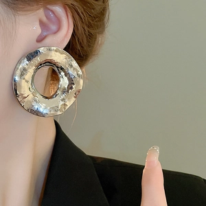 Gros plan de boucles d'oreilles rondes argentées avec texture métallique martelée sur modèle