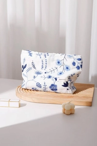 Gros plan détaillé sur la broderie florale bleue d'une trousse en toile blanche chic