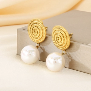 Detail view of gold spiral texture earrings with elegant white round pearls on silk