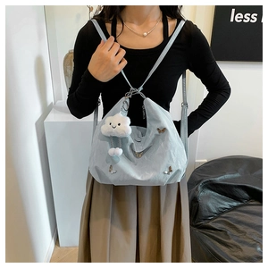 Detail of light blue backpack with metal butterfly and plush cloud charm on shoulder strap