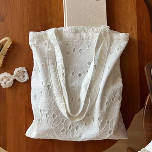 Detail of white eyelet floral embroidery on a cotton tote bag with vintage aesthetics