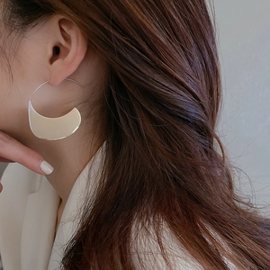 Gros plan d'un mannequin portant de grandes boucles d'oreilles argentées en métal poli