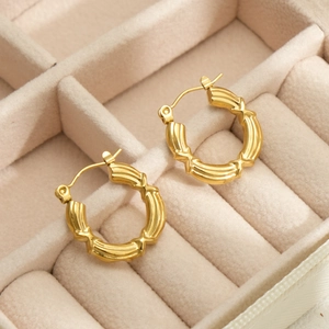 Detail view of 18k gold bamboo-style hoop earrings on a velvet jewelry organizer box