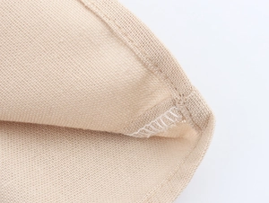 Macro detail of breathable beige mesh fabric with reinforced hem stitching on loose top