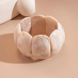 Detail of square acrylic bracelet with marble pattern on a warm minimalist background