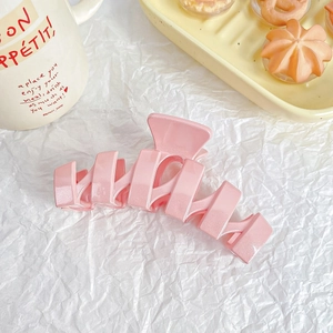 Close-up of pink glitter hair claw clip with pearlescent finish on decorative background