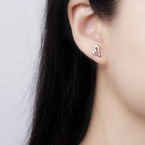 Minimalist silver heart hollow stud earrings worn by a model for a delicate fashion look