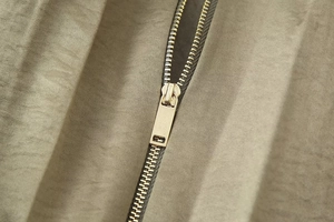 Detailed close-up of high-quality metal zipper and olive woven fabric on pilot jacket