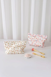 Close-up of floral jacquard cotton makeup bags with brand label on a soft surface