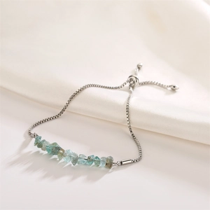 Detail of silver box chain bracelet with blue and green raw stone beads on white silk