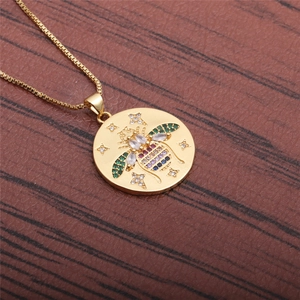 Détail du collier doré avec pendentif abeille serti de pierres précieuses colorées