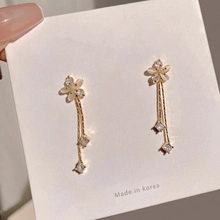 Detail of long gold flower earrings with delicate tassels and square zirconia stones