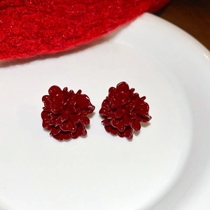 Detailed close-up of layered red flower stud earrings with a glossy enamel finish