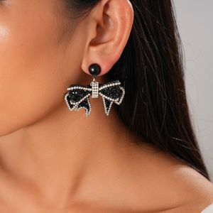 Close-up of black bow earrings with rhinestones on model showing elegant gothic style