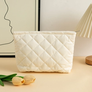 Detail of cream quilted corduroy toiletry bag with soft diamond pattern and metal zipper