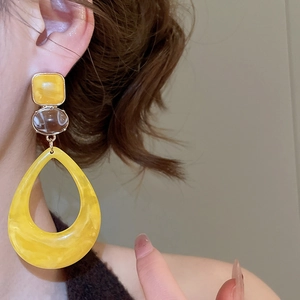 Close-up of geometric marble resin teardrop earrings on a model with gold connectors