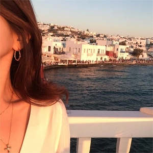 Minimalist gold twisted hoop earrings and cross necklace set on model with sunset view