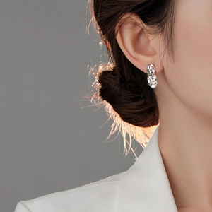Close-up of asymmetrical lava-style silver stud earrings with liquid metal texture