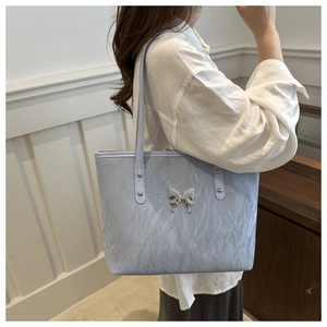 Close-up of light blue pleated tote bag featuring a silver beaded butterfly charm