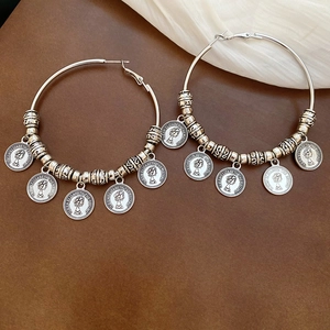 Macro view of silver hoop earrings featuring Queen Elizabeth coin charms and vintage texture