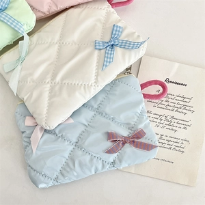 Quilted cosmetic bags in pink, mint, white, and blue with bow accents and zippers