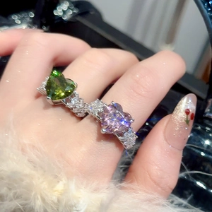 Close-up of heart-shaped emerald and lavender zircon rings with micro-pave silver bands