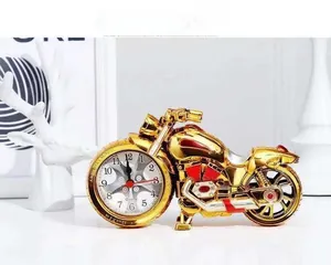 Golden motorcycle shaped alarm clock with analog dial on a clean minimalist white background