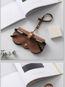 Gros plan d'une pochette à lunettes en cuir marron avec bouton pression et cordon réglable