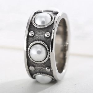 Gros plan d'une bague vintage argentée avec perles blanches et détails gravés