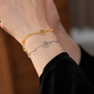 Close-up of gold and silver bracelets featuring starburst compass charms with zircon stones