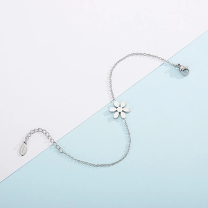 Minimalist stainless steel daisy flower bracelet with silver finish on blue background