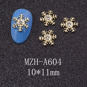 Close-up of golden snowflake nail charms with a center crystal on a blue nail tip