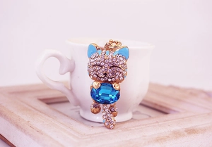 Detail of fortune cat keychain with white rhinestones and large blue oval gemstone