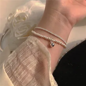 Double-layered bracelet with silver chain, white pearls and a minimalist silver ball pendant