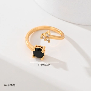 Detail view of gold adjustable ring featuring black gemstone and zirconia on white background