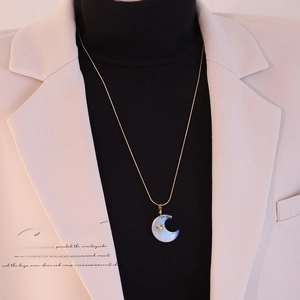 Dettaglio della collana a mezza luna con farfalla dorata su pietra di opale blu chiaro