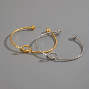 Dettaglio ravvicinato di bracciali a nodo oro e argento con finitura in metallo lucido